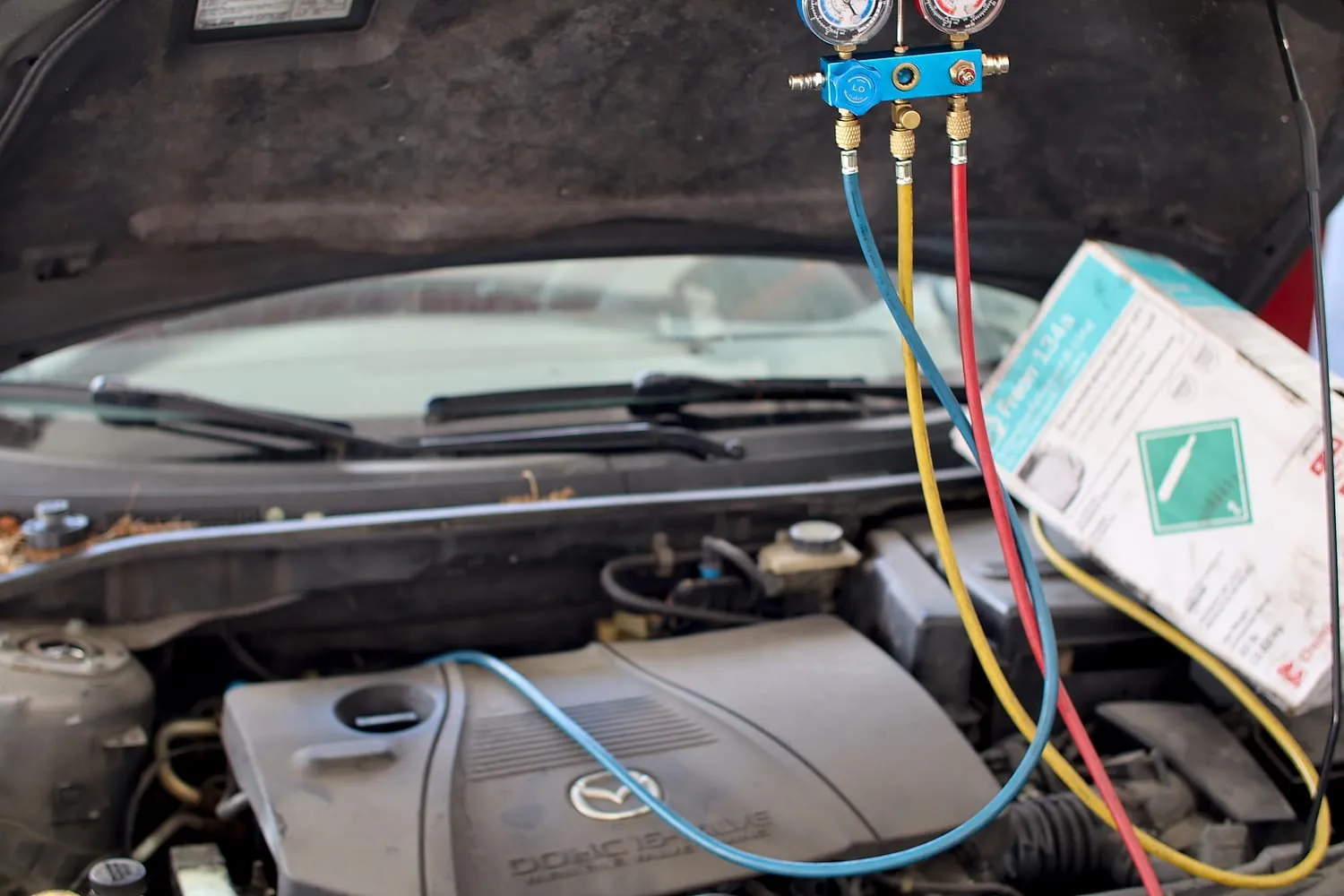 A/C manifold gauges connected to a car during air-conditioning service at Japanese Auto Tech